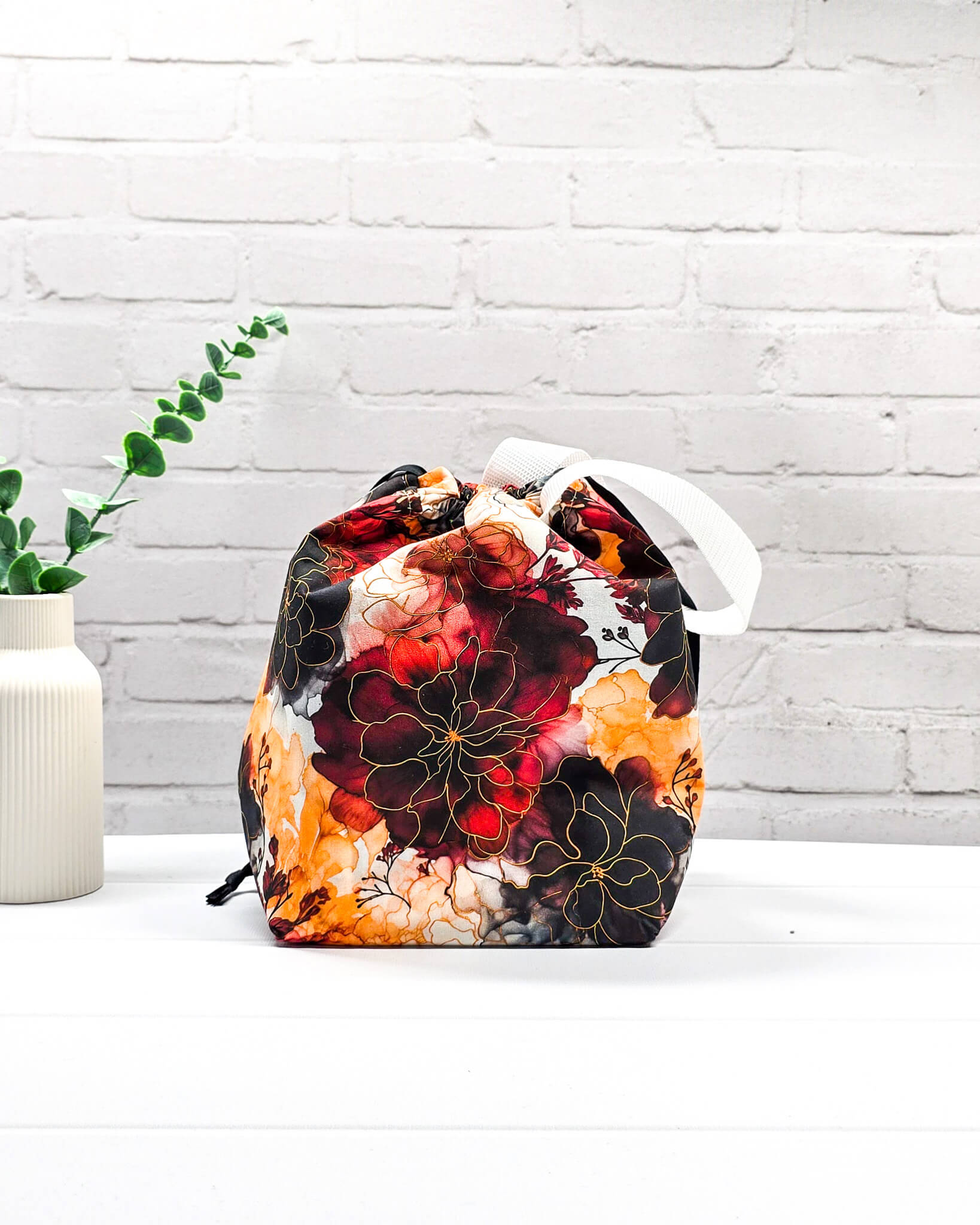Projekttasche Tuva M aus Baumwolle mit weinroten und senfgelben Aquarell-Blumen, schwarzem Kordelzug und heller Schlaufe. Handgenäht in Bayern von Nadelmikado. 