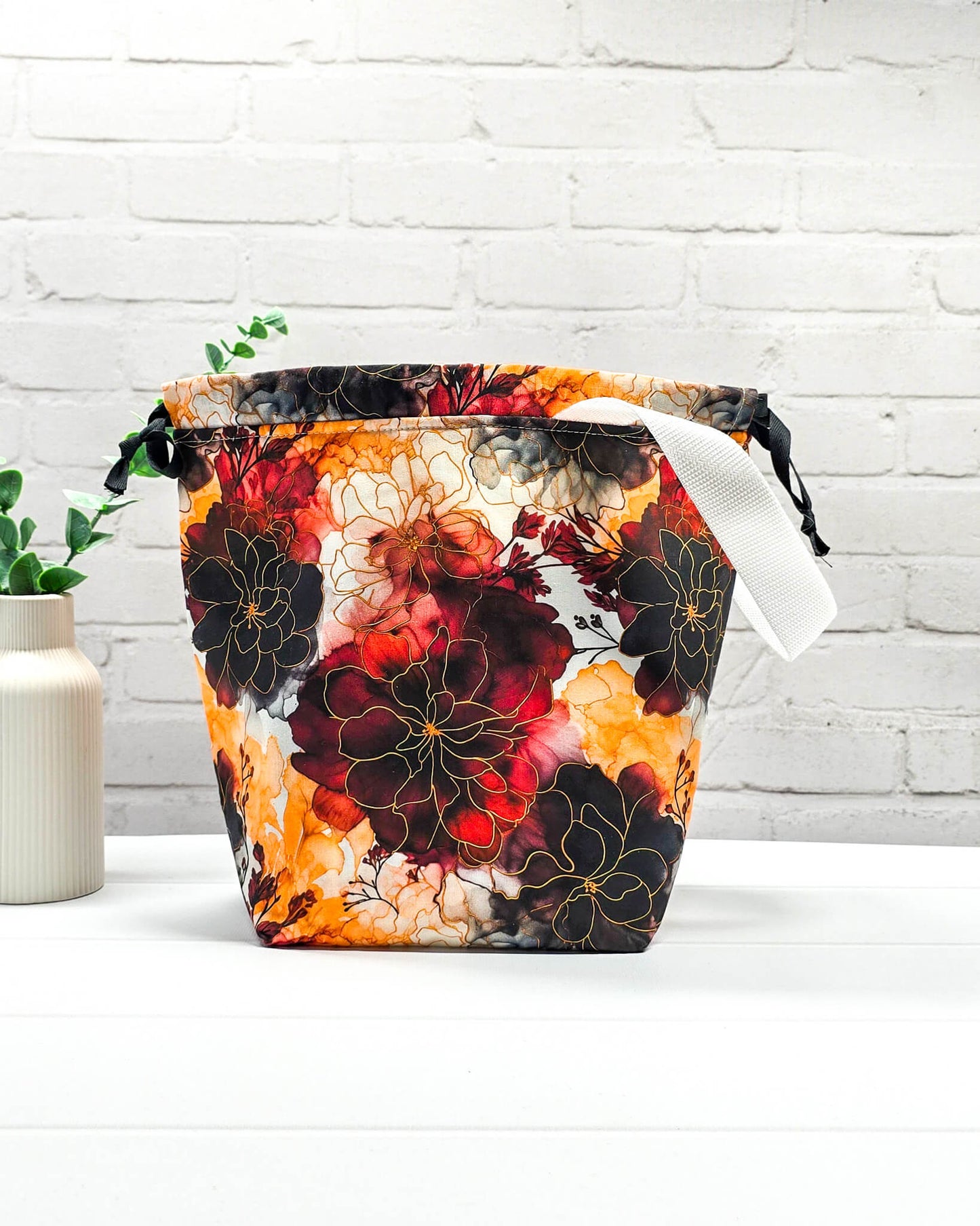 Projekttasche Tuva M aus Baumwolle mit weinroten und senfgelben Aquarell-Blumen, schwarzem Kordelzug und heller Schlaufe. Handgenäht in Bayern von Nadelmikado. 