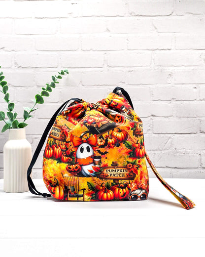 Projekttasche Tuva M aus buntem Baumwollstoff mit Geistern, Kürbissen, „Pumpkin Patch“-Schildern und schwarzem Kordelzug. Handgenäht in Bayern von Nadelmikado. 
