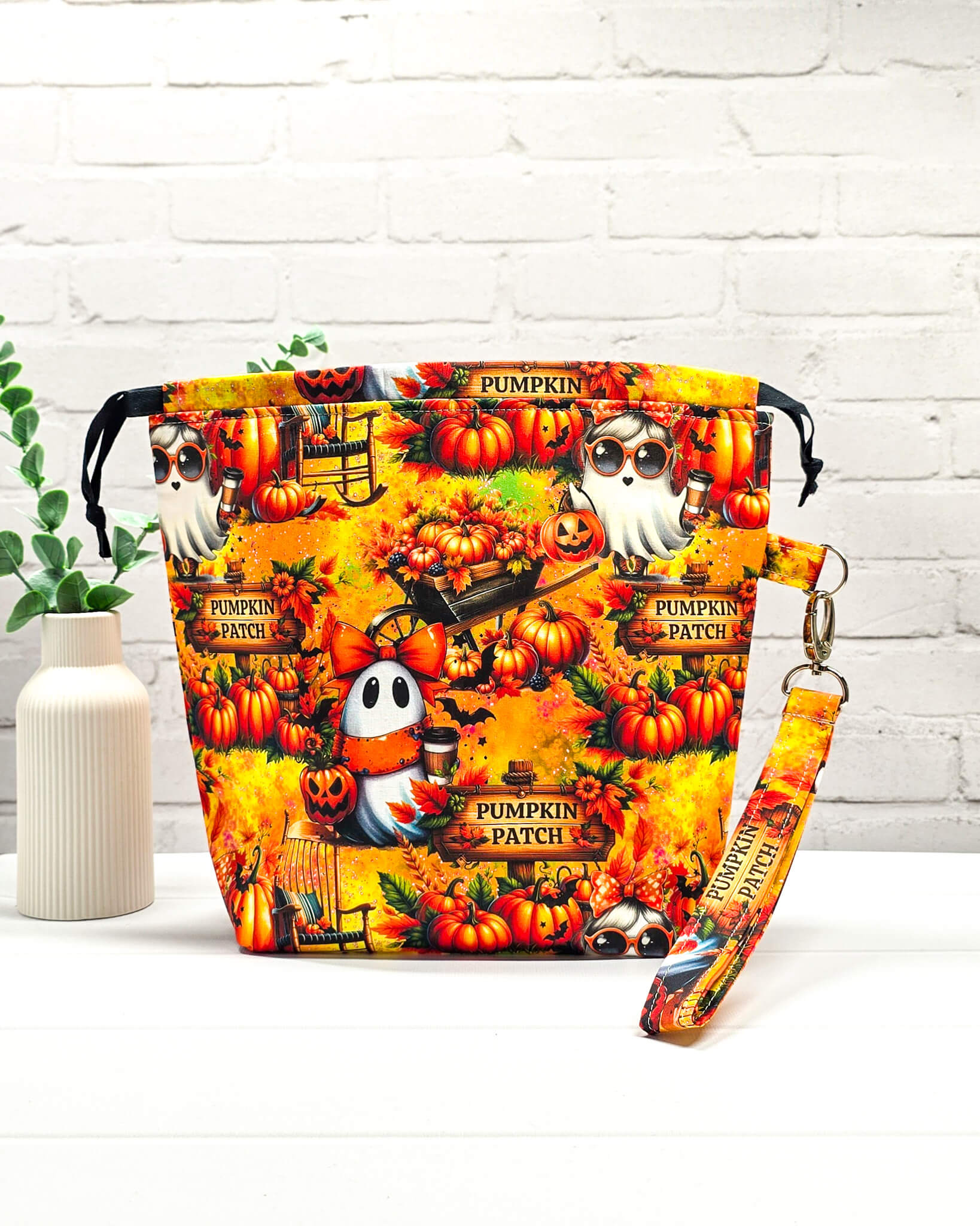 Projekttasche Tuva M aus buntem Baumwollstoff mit Geistern, Kürbissen, „Pumpkin Patch“-Schildern und schwarzem Kordelzug. Handgenäht in Bayern von Nadelmikado. 