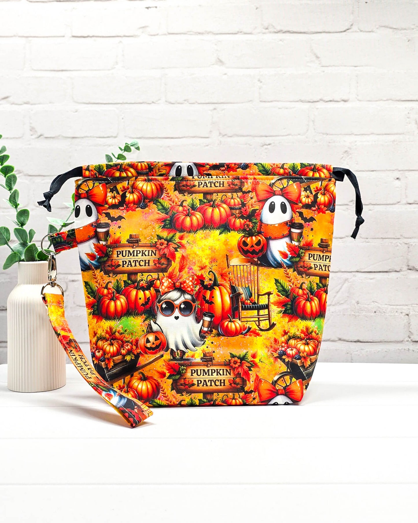 Projekttasche Tuva M aus buntem Baumwollstoff mit Geistern, Kürbissen, „Pumpkin Patch“-Schildern und schwarzem Kordelzug. Handgenäht in Bayern von Nadelmikado. 