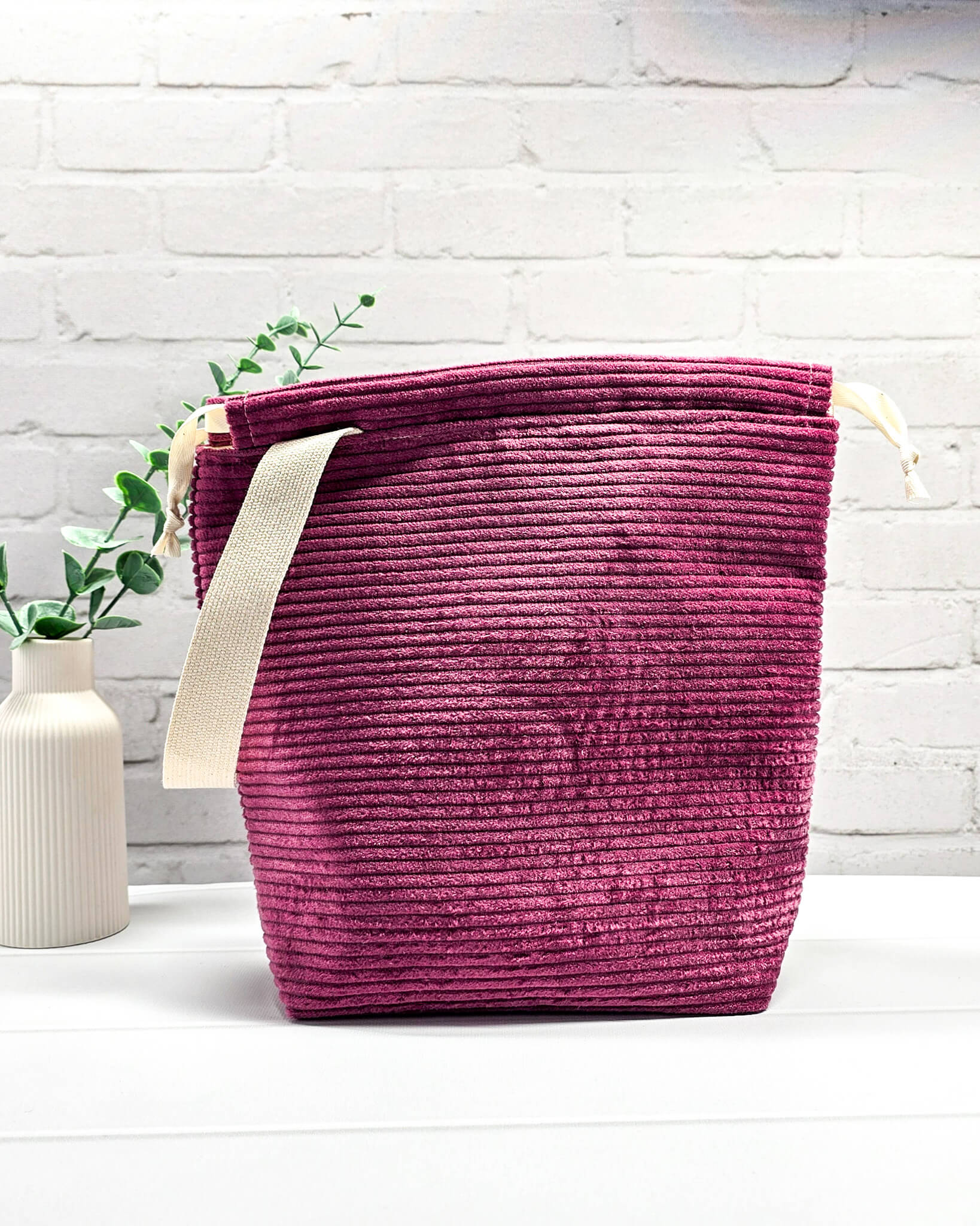 Bestickte Projekttasche Tuva M aus beerefarbenem Breitcord mit dem Schriftzug KNITTING, Kordelzug und cremefarbenem Tragegurt. Bietet Platz für 400g Wolle und schützt das Strickzeug vor Verheddern. Handgenäht in Bayern von Nadelmikado.