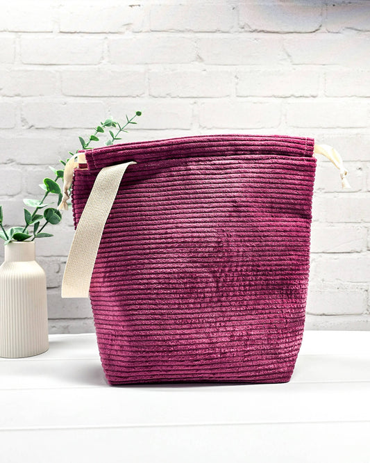 Bestickte Projekttasche Tuva M aus beerefarbenem Breitcord mit dem Schriftzug KNITTING, Kordelzug und cremefarbenem Tragegurt. Bietet Platz für 400g Wolle und schützt das Strickzeug vor Verheddern. Handgenäht in Bayern von Nadelmikado.