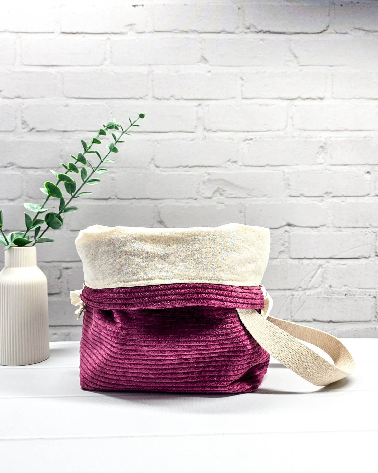 Bestickte Projekttasche Tuva M aus beerefarbenem Breitcord mit dem Schriftzug KNITTING, Kordelzug und cremefarbenem Tragegurt. Bietet Platz für 400g Wolle und schützt das Strickzeug vor Verheddern. Handgenäht in Bayern von Nadelmikado.