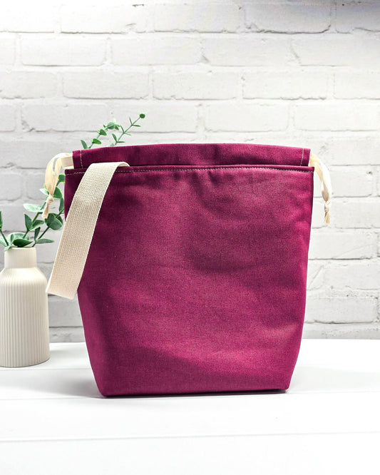 Projekttasche Tuva M aus hellem Canvas und beerefarbenem Stoff mit gesticktem Eulenmotiv, cremefarbenem Kordelzug und Tragegurt. Bietet Platz für 400g Wolle und schützt das Strickzeug vor Verheddern. Handgenäht in Bayern von Nadelmikado.