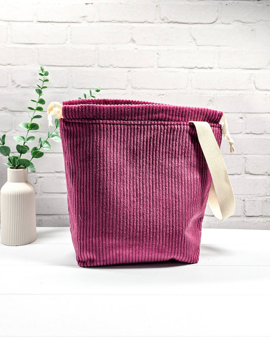 Beerenfarbene Projekttasche Tuva M aus Cordstoff mit einem hellen Gurtband-Henkel an der Seite und cremefarbenen Kordeln, handgenäht von Nadelmikado in Bayern. 