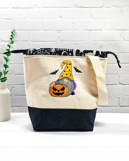Projekttasche Tuva M aus hellem Canvas mit gesticktem Halloween Gnom, Kürbis und schwarzem Kordelzugkragen. Handgenäht in Bayern von Nadelmikado.