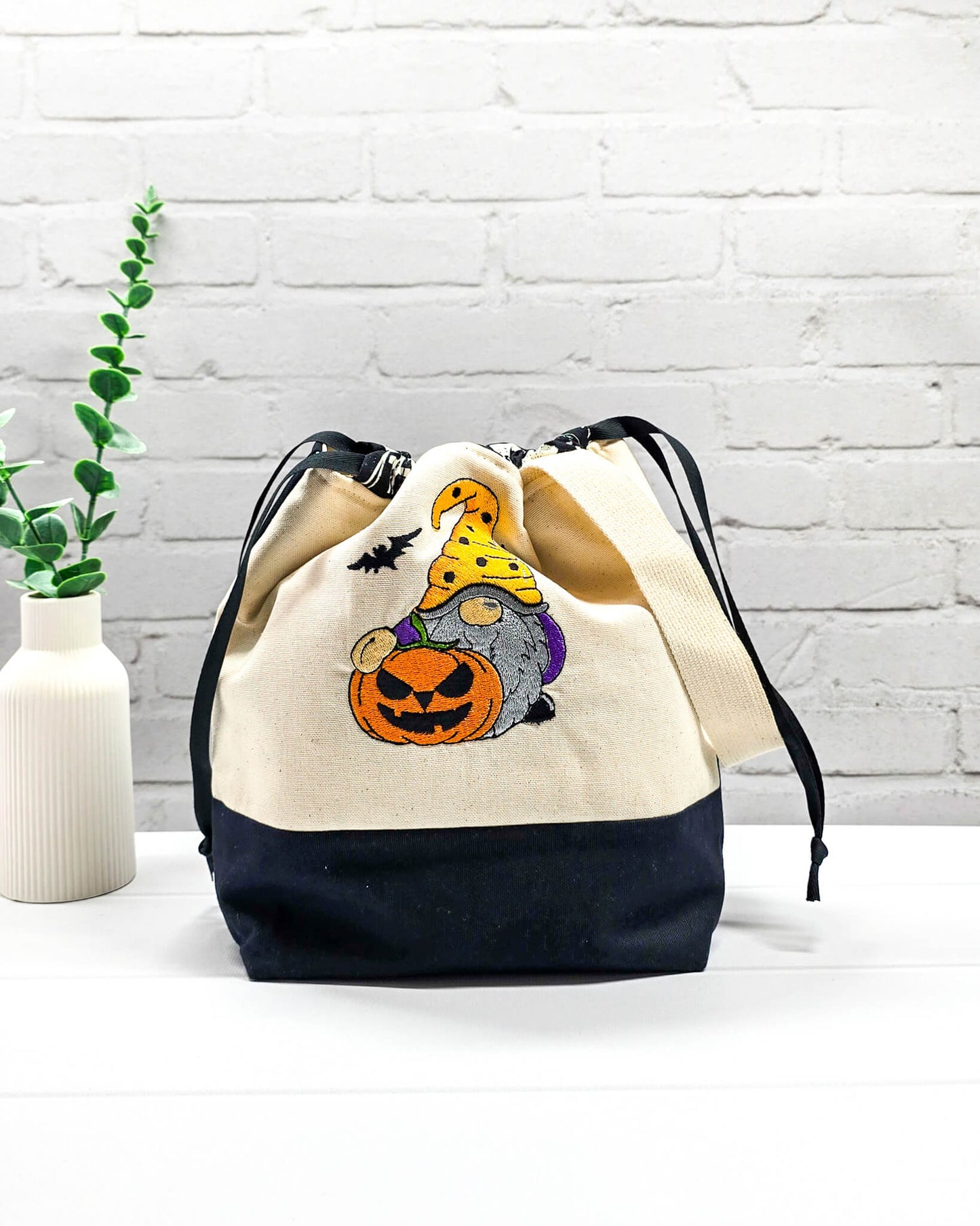 Projekttasche Tuva M aus hellem Canvas mit gesticktem Halloween Gnom, Kürbis und schwarzem Kordelzugkragen. Handgenäht in Bayern von Nadelmikado.