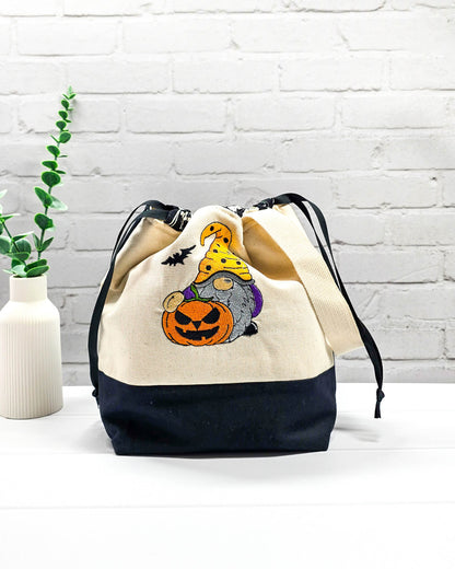 Projekttasche Tuva M aus hellem Canvas mit gesticktem Halloween Gnom, Kürbis und schwarzem Kordelzugkragen. Handgenäht in Bayern von Nadelmikado.