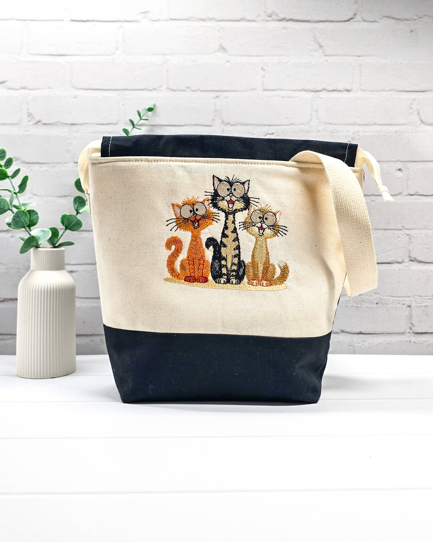 Projekttasche Tuva M aus hellem Canvas und Schwarz mit gesticktem lustigen Katzen Trio und Kordelzugverschluss. Handgenäht in Bayern von Nadelmikado.