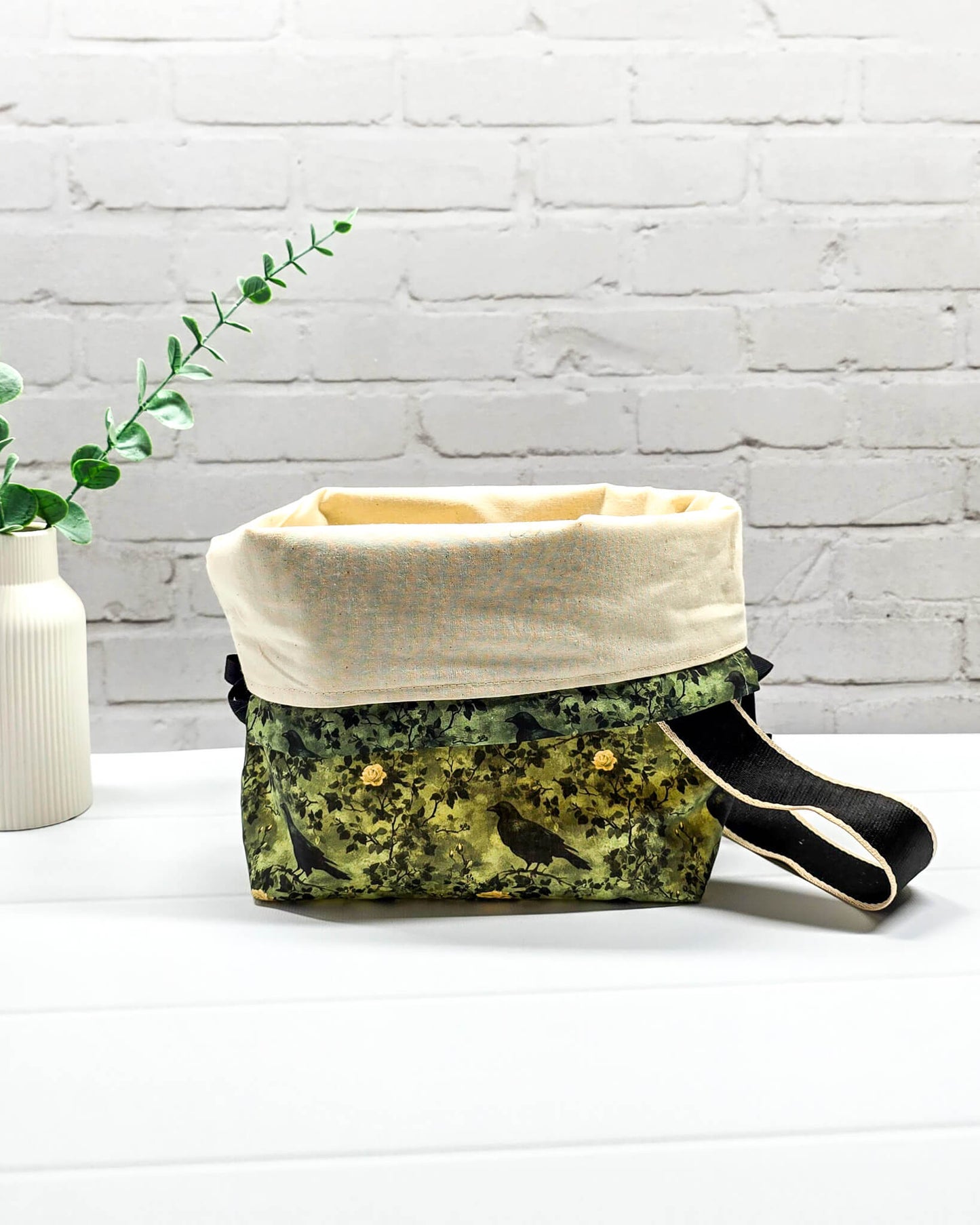 Mittlere grüne Projekttasche mit Trageriemen, gemustert mit Raben und Rosen, genutzt als Strickbeutel für ein Tuchprojekt mit bis zu 400g Wolle. Handgenäht in Bayern von Nadelmikado.