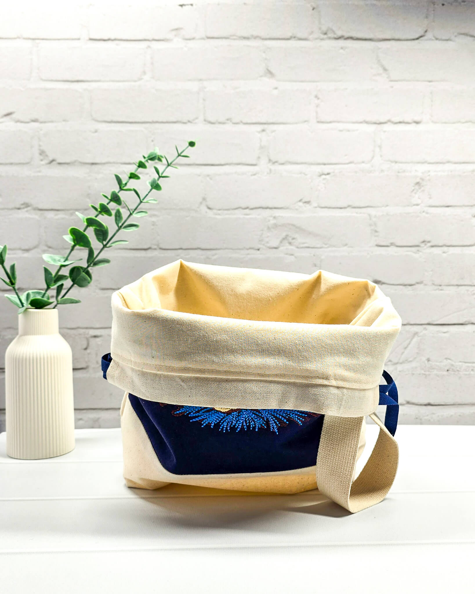 Projekttasche Tuva M aus dunkelblauem und hellem Canvas-Stoff mit gesticktem blauen Seestern und Muschel-Motiv, blauem Kordelzug und cremefarbenem Tragegurt. Bietet Platz für 400g Wolle und schützt das Strickzeug vor Verheddern. Handgenäht in Bayern von Nadelmikado.