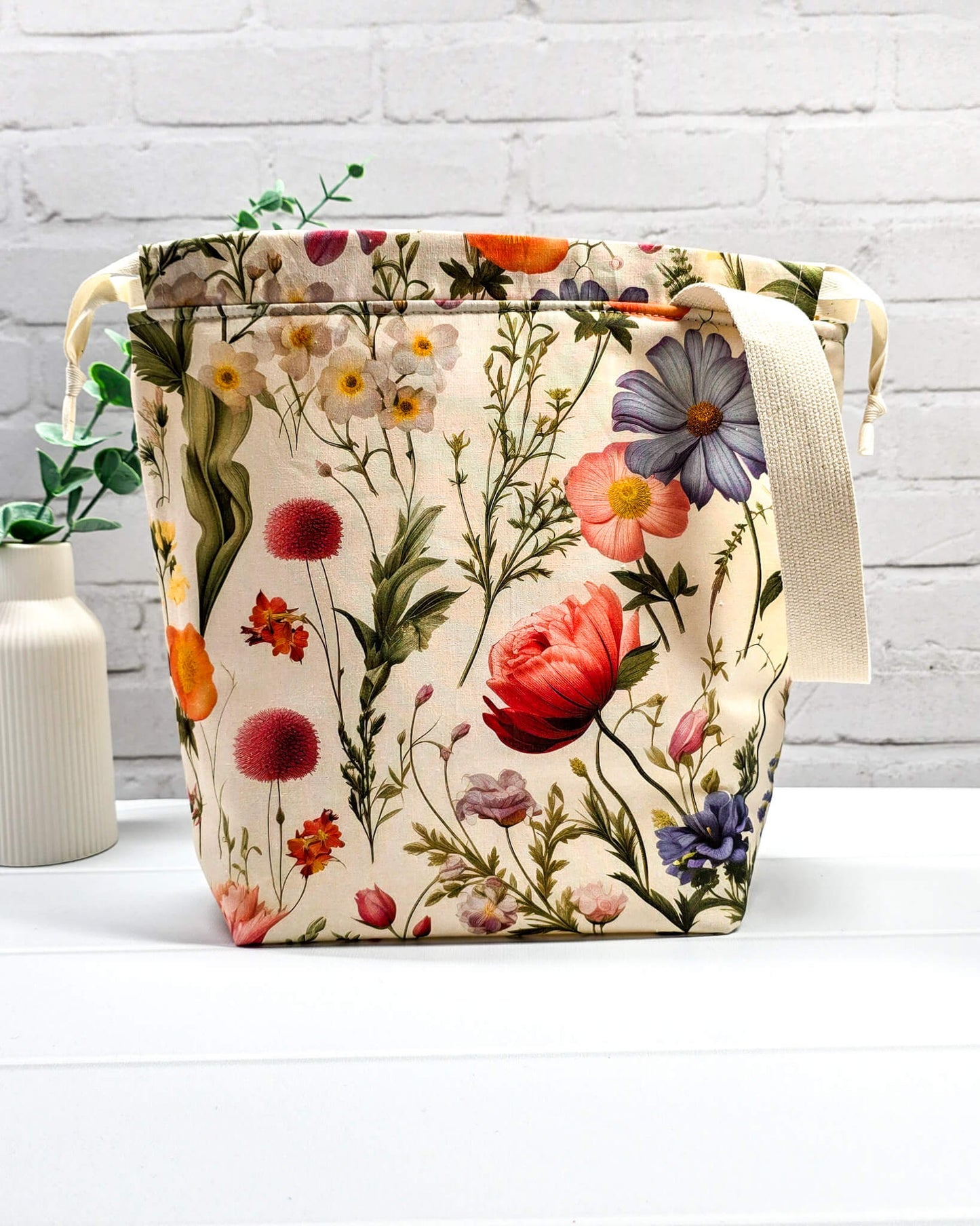 Projektbeutel mit buntem Blumenmuster für die sichere Aufbewahrung deines Tuch-Projekts unterwegs. Handgenäht in Bayern von Nadelmikado.
