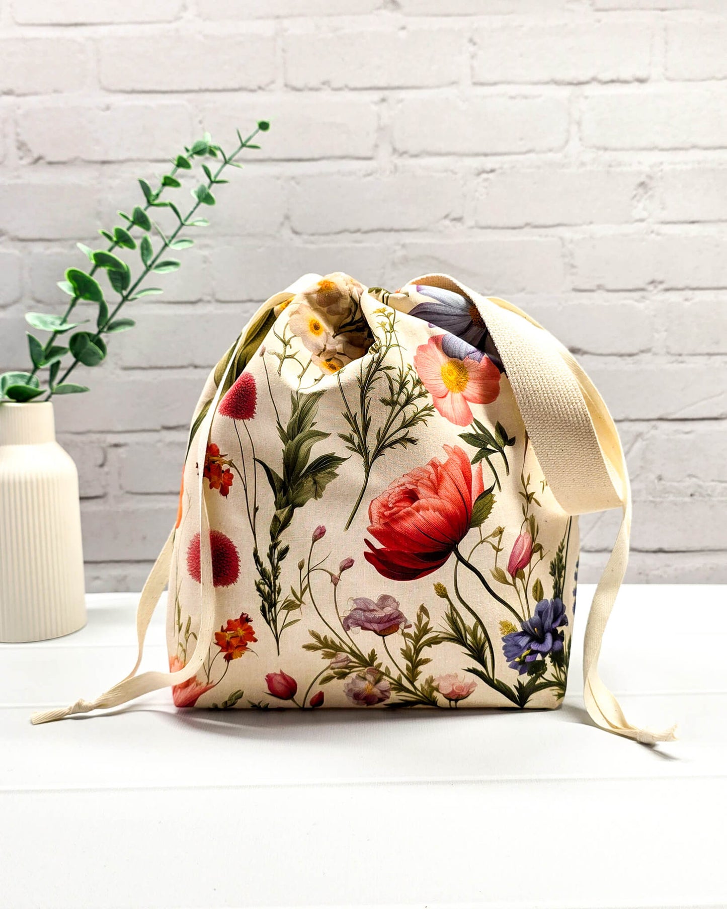 Projektbeutel mit buntem Blumenmuster für die sichere Aufbewahrung deines Tuch-Projekts unterwegs. Handgenäht in Bayern von Nadelmikado.
