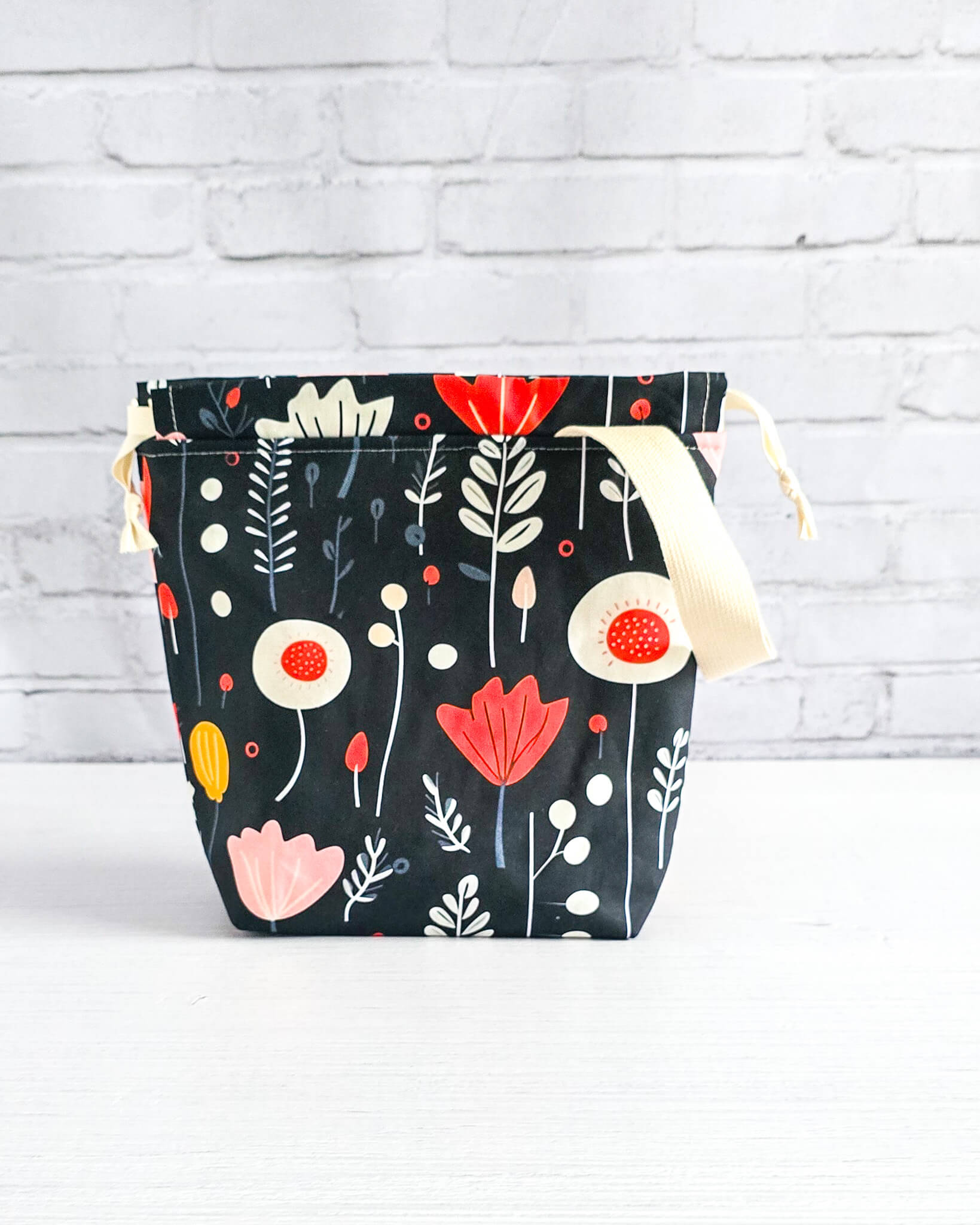 Projekttasche Tuva S Autumn Folk mit grafischem Blumenmuster auf dunklem Stoff - handgenäht in Bayern von Nadelmikado