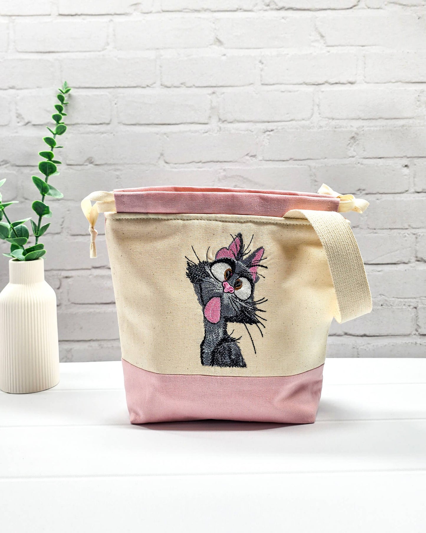 Projekttasche Tuva S aus hellem Canvas und Rosa mit gestickter frecher Katze und Kordelzugkragen. Handgenäht in Bayern von Nadelmikado.