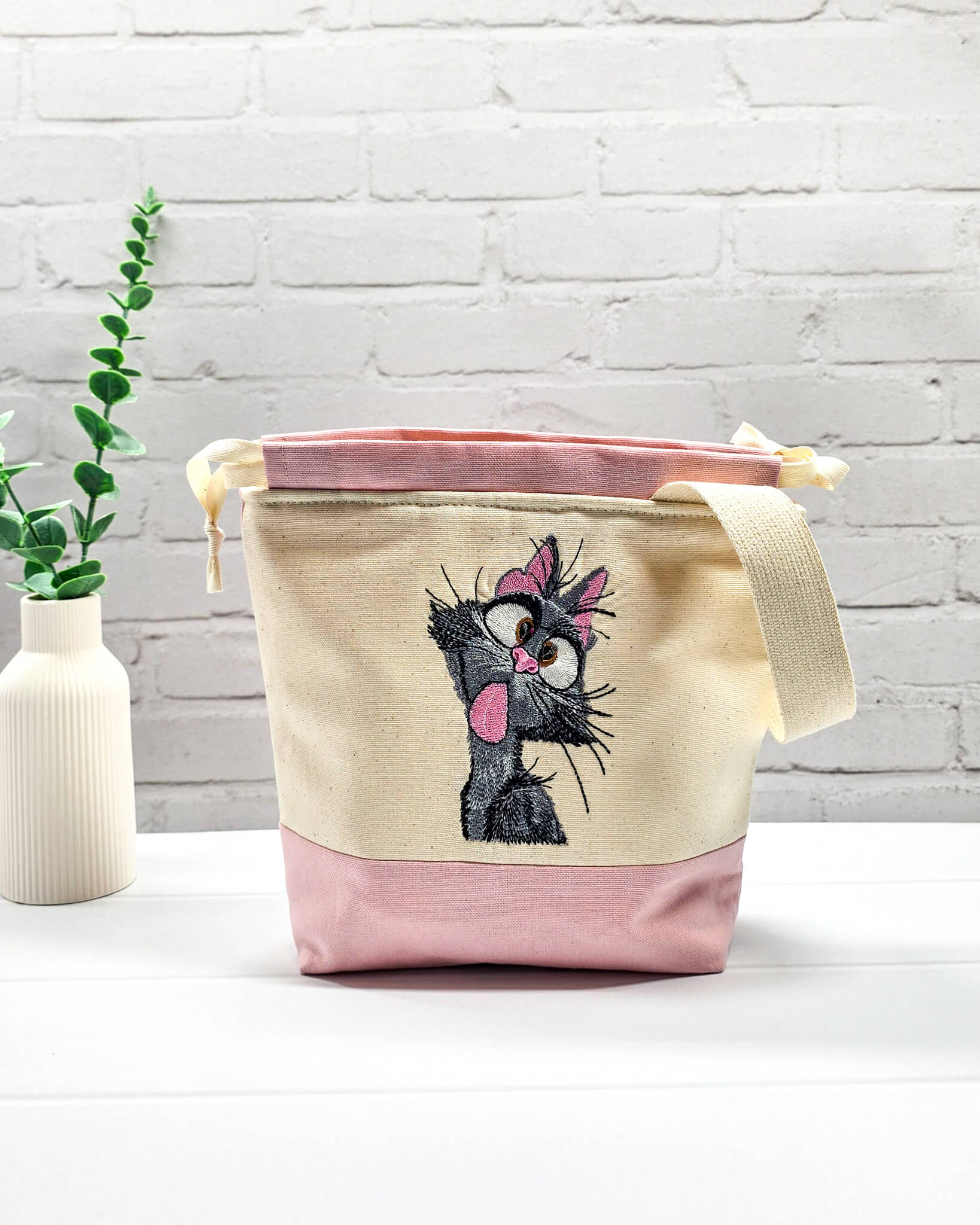 Projekttasche Tuva S aus hellem Canvas und Rosa mit gestickter frecher Katze und Kordelzugkragen. Handgenäht in Bayern von Nadelmikado.