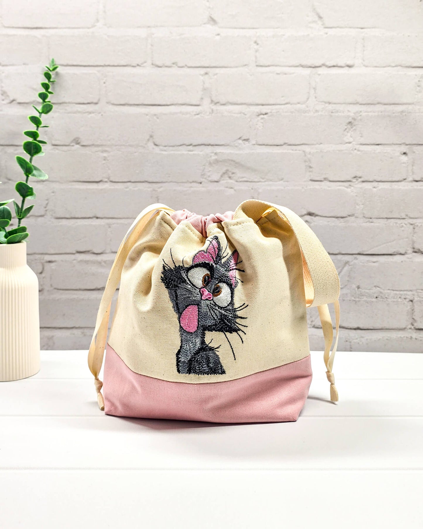Projekttasche Tuva S aus hellem Canvas und Rosa mit gestickter frecher Katze und Kordelzugkragen. Handgenäht in Bayern von Nadelmikado.
