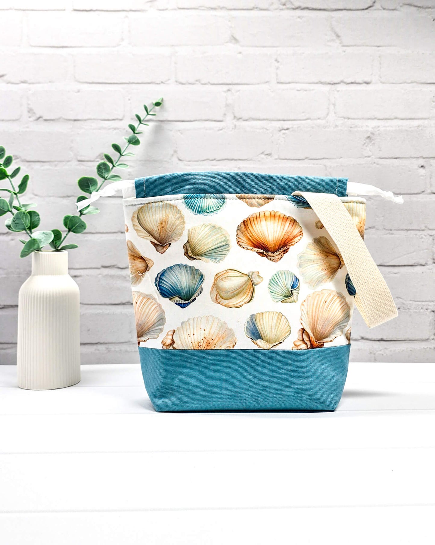 Projektbeutel mit Muschelmuster, blauem Canvas-Boden, weißem Kordelzug und Tragegurt. Platz für 200g Wolle. Handgenäht in Bayern von Nadelmikado.