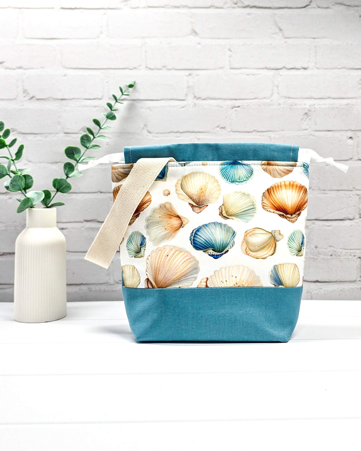 Projektbeutel mit Muschelmuster, blauem Canvas-Boden, weißem Kordelzug und Tragegurt. Platz für 200g Wolle. Handgenäht in Bayern von Nadelmikado.