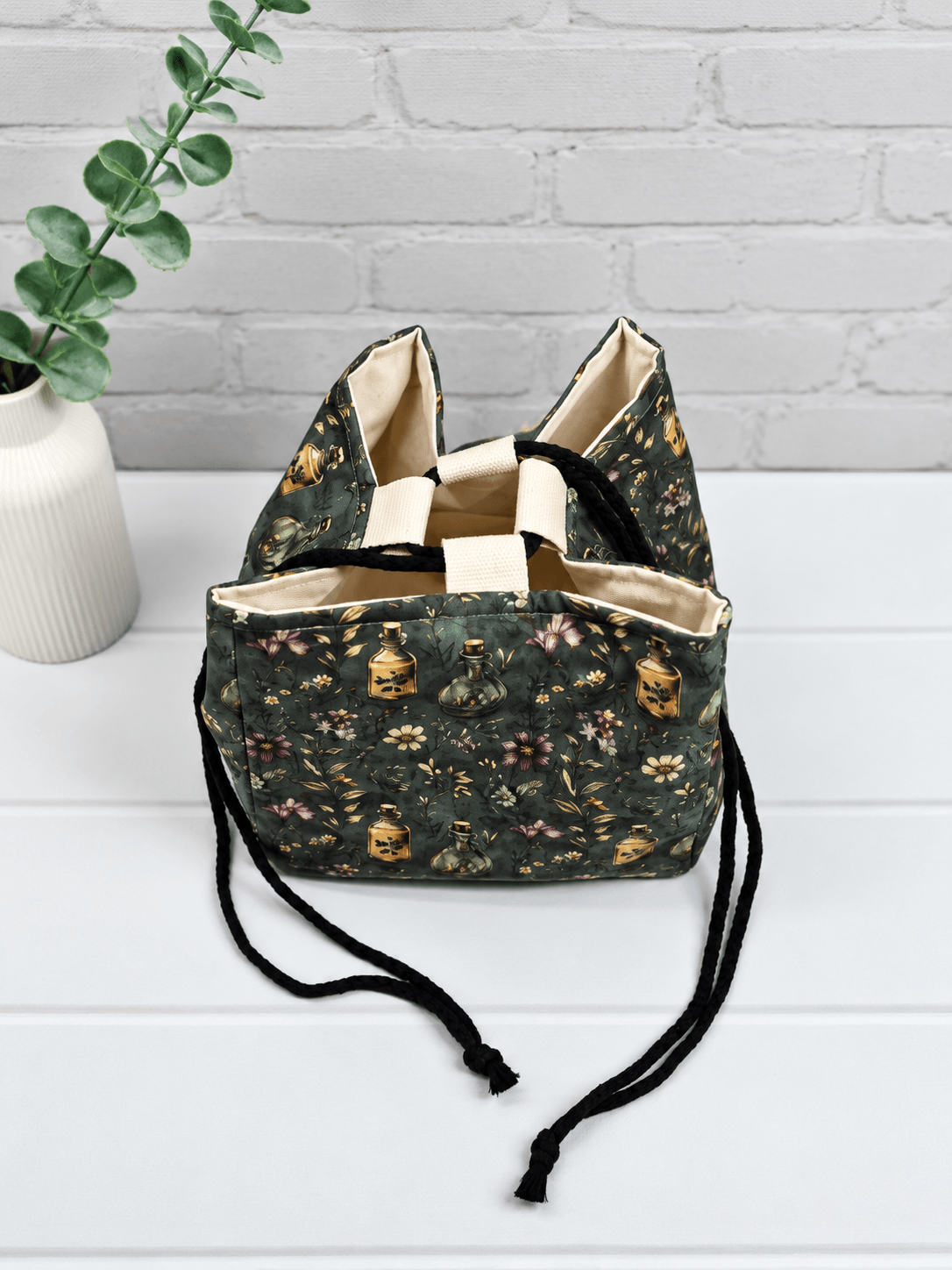Rice Bag mit Blüten, Zweigen und Apothekerfläschchen auf dunklem Stoff. Handgenäht in Bayern von NadelMikado.