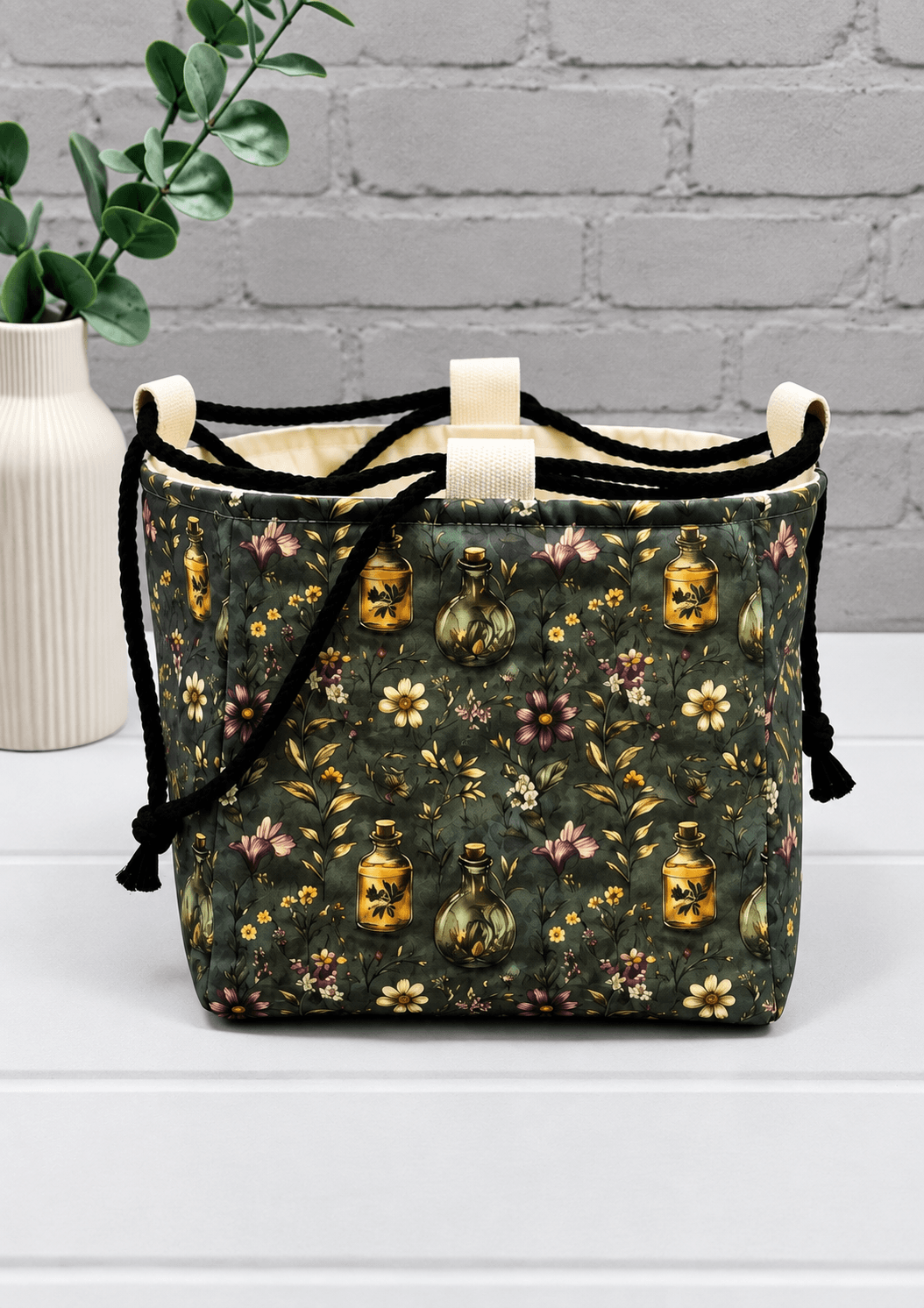 Rice Bag mit Blüten, Zweigen und Apothekerfläschchen auf dunklem Stoff. Handgenäht in Bayern von NadelMikado.