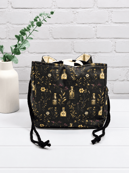 Rice Bag mit botanischem Muster aus Fläschchen, Blüten und Zweigen auf dunklem Stoff. Handgenäht in Bayern von NadelMikado.