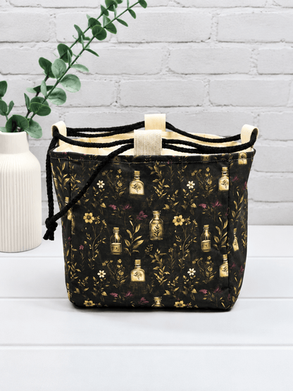 Rice Bag mit botanischem Muster aus Fläschchen, Blüten und Zweigen auf dunklem Stoff. Handgenäht in Bayern von NadelMikado.