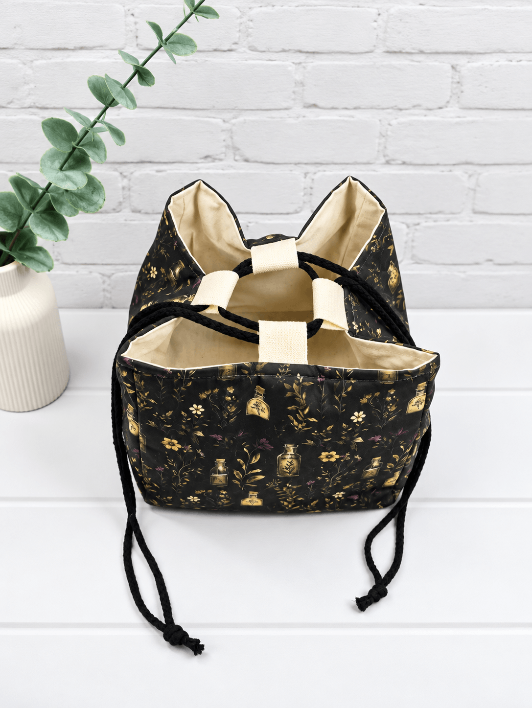 Rice Bag mit botanischem Muster aus Fläschchen, Blüten und Zweigen auf dunklem Stoff. Handgenäht in Bayern von NadelMikado.