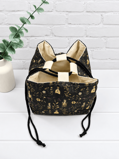 Rice Bag mit botanischem Muster aus Fläschchen, Blüten und Zweigen auf dunklem Stoff. Handgenäht in Bayern von NadelMikado.