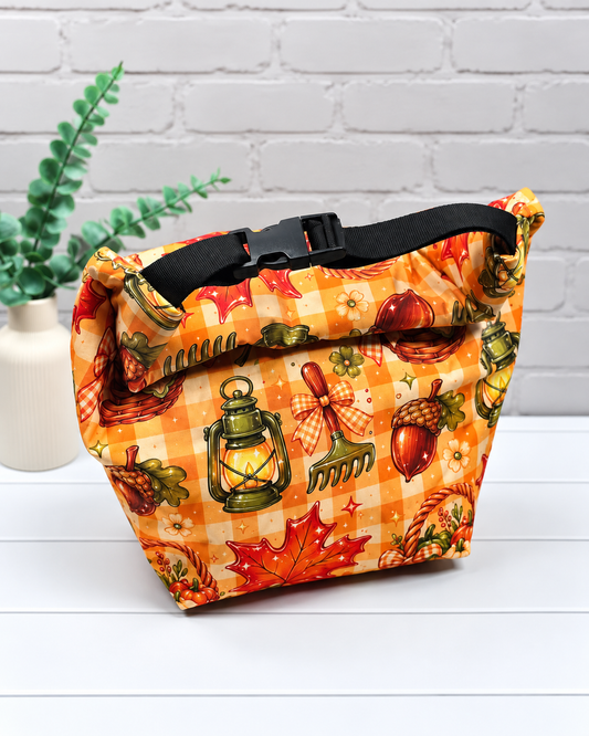 Rolltop-Projekttasche Rika mit orangefarbenem Karomuster, Herbstblättern, Eicheln, Laternen und Erntekörben mit Kürbissen. Handgenäht in Bayern von Nadelmikado.
