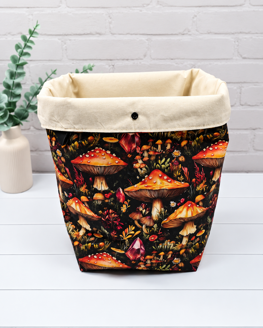 Rolltop-Projekttasche Rika mit orange-roten Fliegenpilzen, roten Kristallen und herbstlichen Waldpflanzen auf schwarzem Stoff. Handgenäht in Bayern von Nadelmikado.