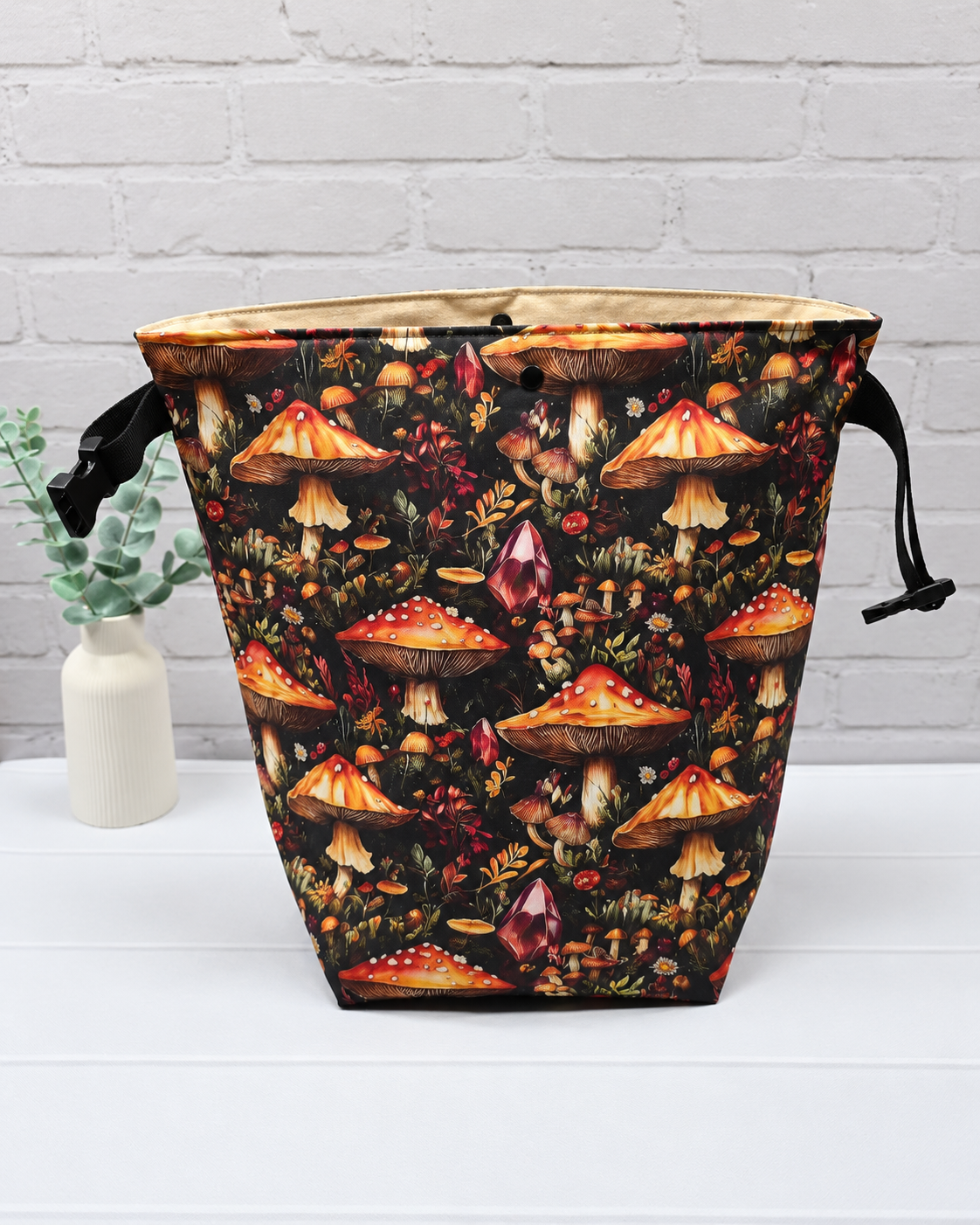 Rolltop-Projekttasche Rika mit orange-roten Fliegenpilzen, roten Kristallen und herbstlichen Waldpflanzen auf schwarzem Stoff. Handgenäht in Bayern von Nadelmikado.