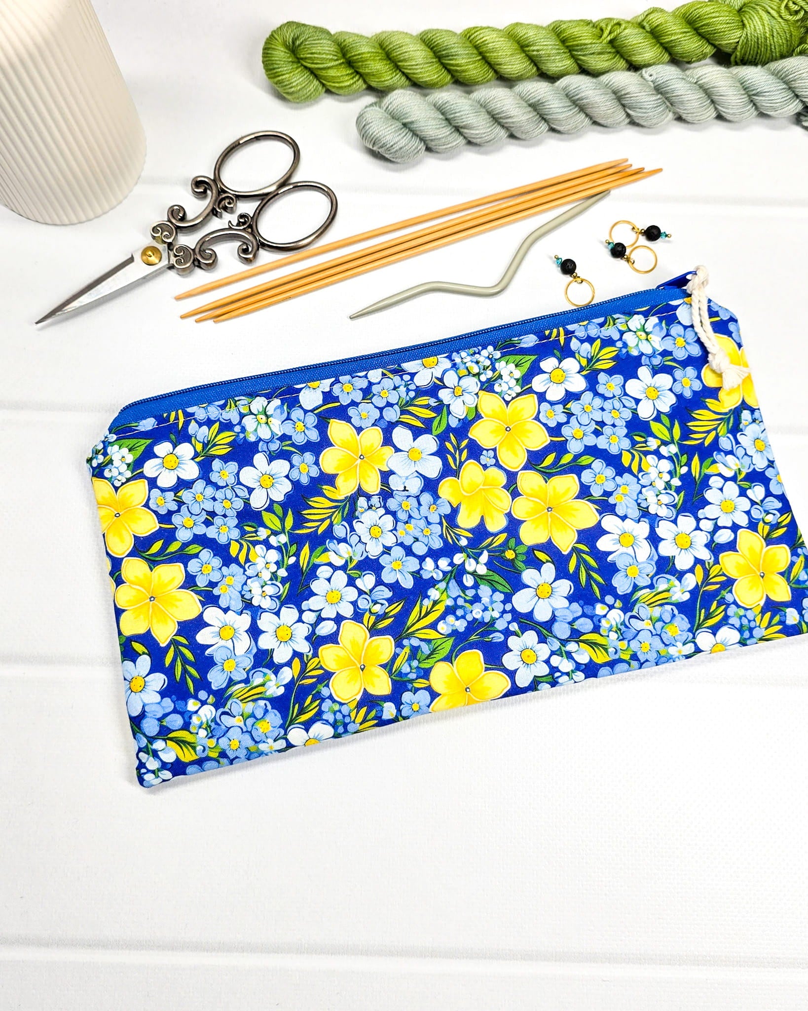 Flache Reißverschlusstasche mit blauem Reißverschluss, hellem Kordel-Zipper und buntem Blumenmuster mit gelben und blauen Blüten. Handgenäht in Bayern von Nadelmikado.