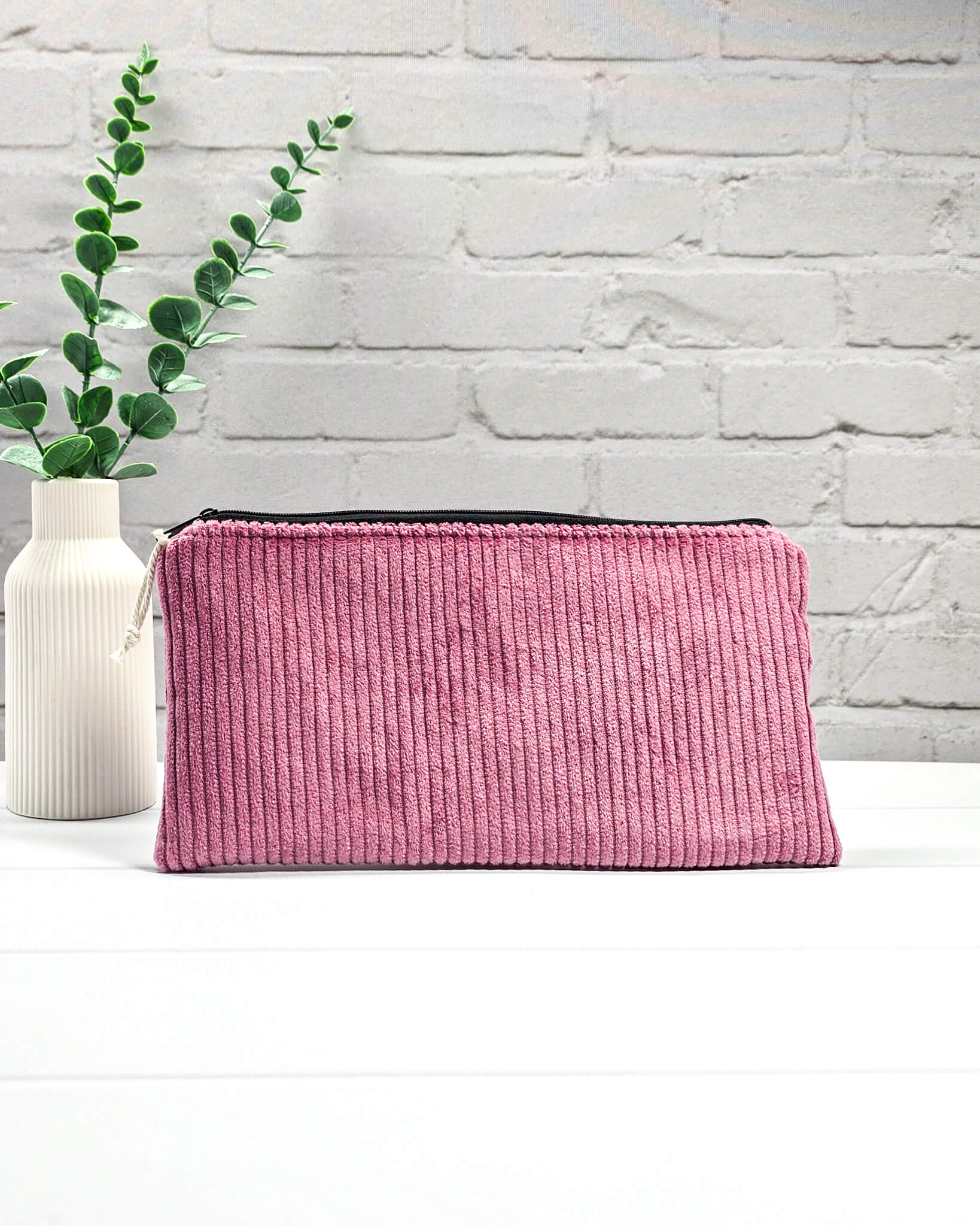 Kleine Reißverschlusstasche aus altrosafarbenem Cord-Stoff für Strickzubehör, flach liegend auf weißem Untergrund mit Schere, Garn und Nadeln. Handgenäht in Bayern von Nadelmikado.