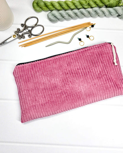 Kleine Reißverschlusstasche aus altrosafarbenem Cord-Stoff für Strickzubehör, flach liegend auf weißem Untergrund mit Schere, Garn und Nadeln. Handgenäht in Bayern von Nadelmikado.