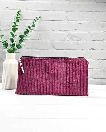 Kleine Reißverschlusstasche aus beerenfarbenem Cord-Stoff auf hellem Untergrund mit Strickzubehör. Handgenäht in Bayern von Nadelmikado. 