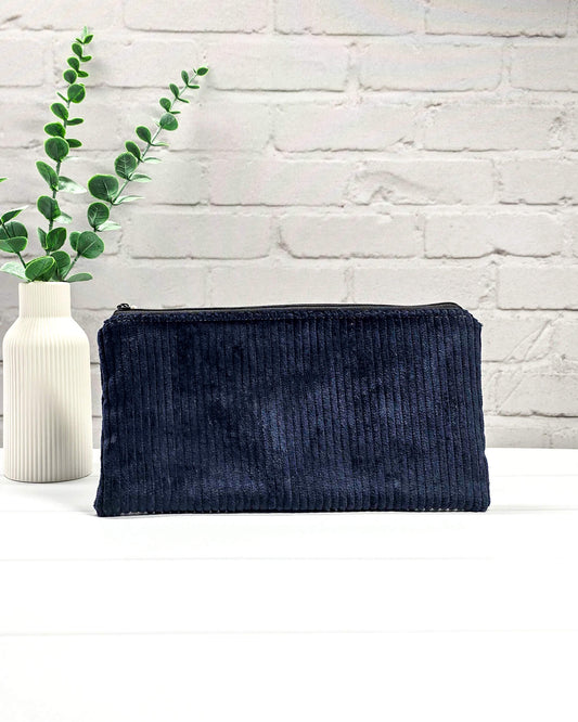 Kleine Reißverschlusstasche aus dunkelblauem Cord-Stoff für Strickzubehör, flach liegend auf weißem Untergrund mit Schere, Garn und Nadeln. Handgenäht in Bayern von Nadelmikado.
