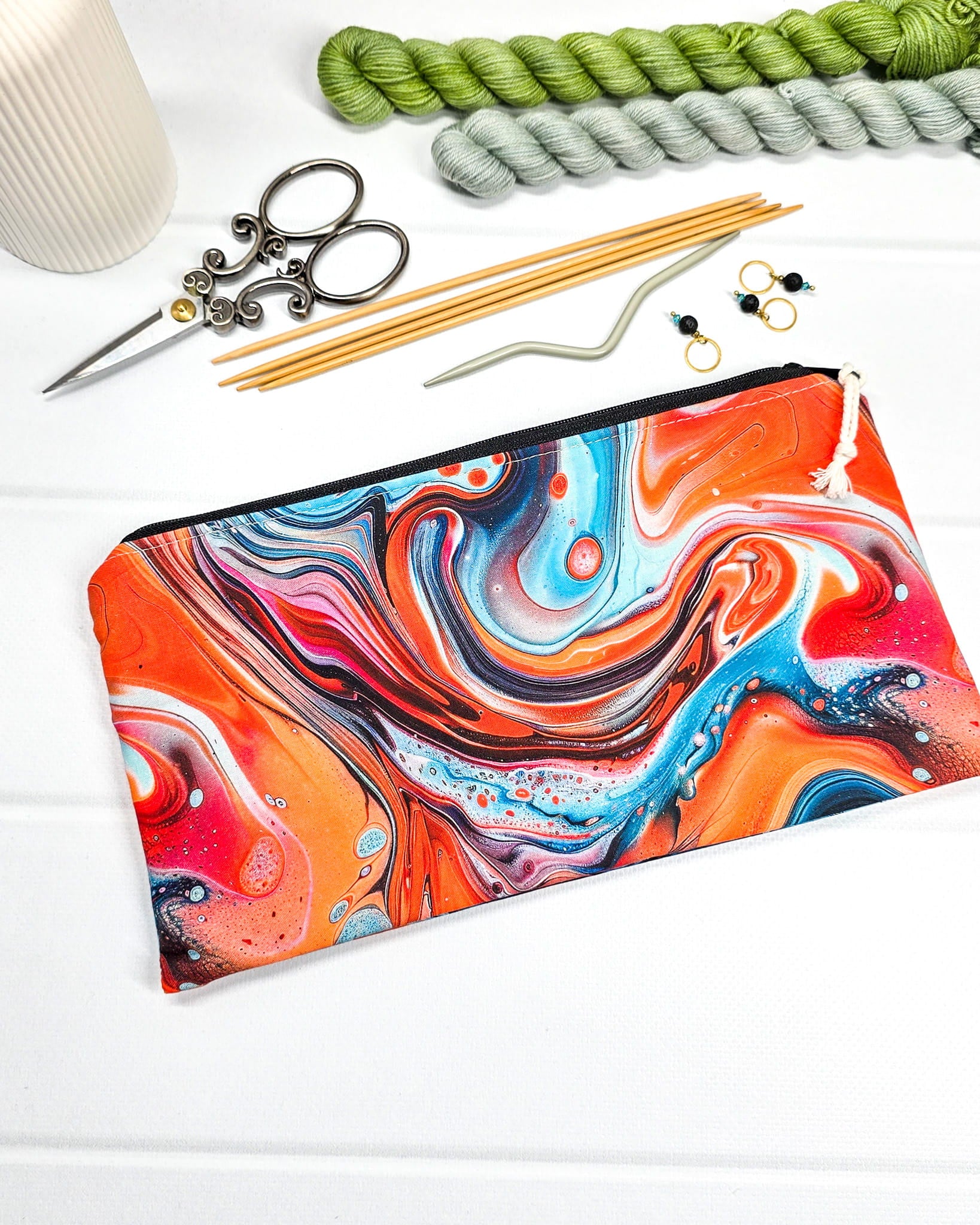 Längliches Täschchen mit schwarzem Reißverschluss, hellem Kordel-Zipper und buntem, fließendem Muster im Fluid-Art-Design mit Orange und Türkis. Handgenäht in Bayern von Nadelmikado.
