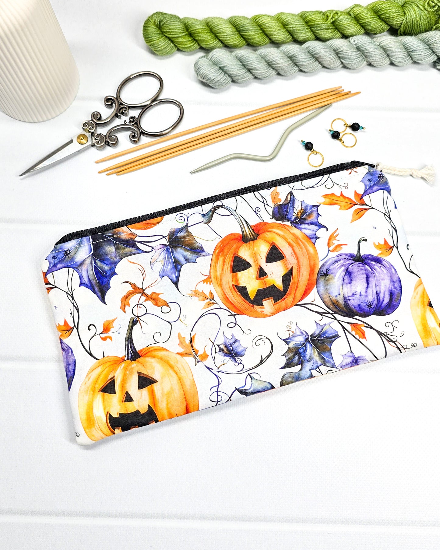 Handgenähte Zubehörtasche mit schwarzem Reißverschluss, weißem Kordel-Zipper und herbstlichen Halloween-Kürbissen auf hellem Stoff.