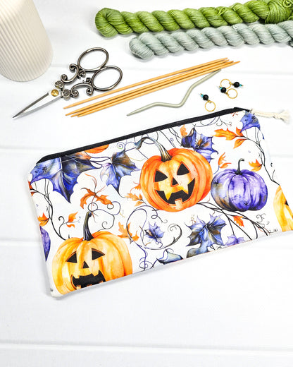 Handgenähte Zubehörtasche mit schwarzem Reißverschluss, weißem Kordel-Zipper und herbstlichen Halloween-Kürbissen auf hellem Stoff.