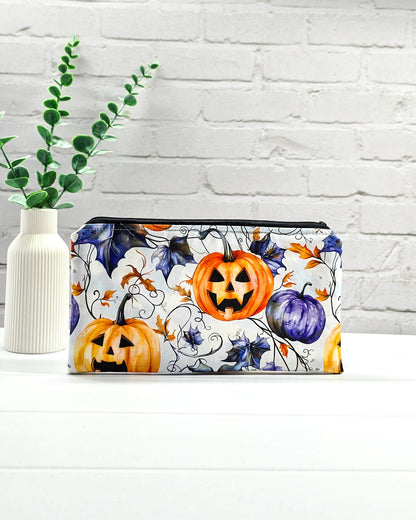 Handgenähte Zubehörtasche mit schwarzem Reißverschluss, weißem Kordel-Zipper und herbstlichen Halloween-Kürbissen auf hellem Stoff.