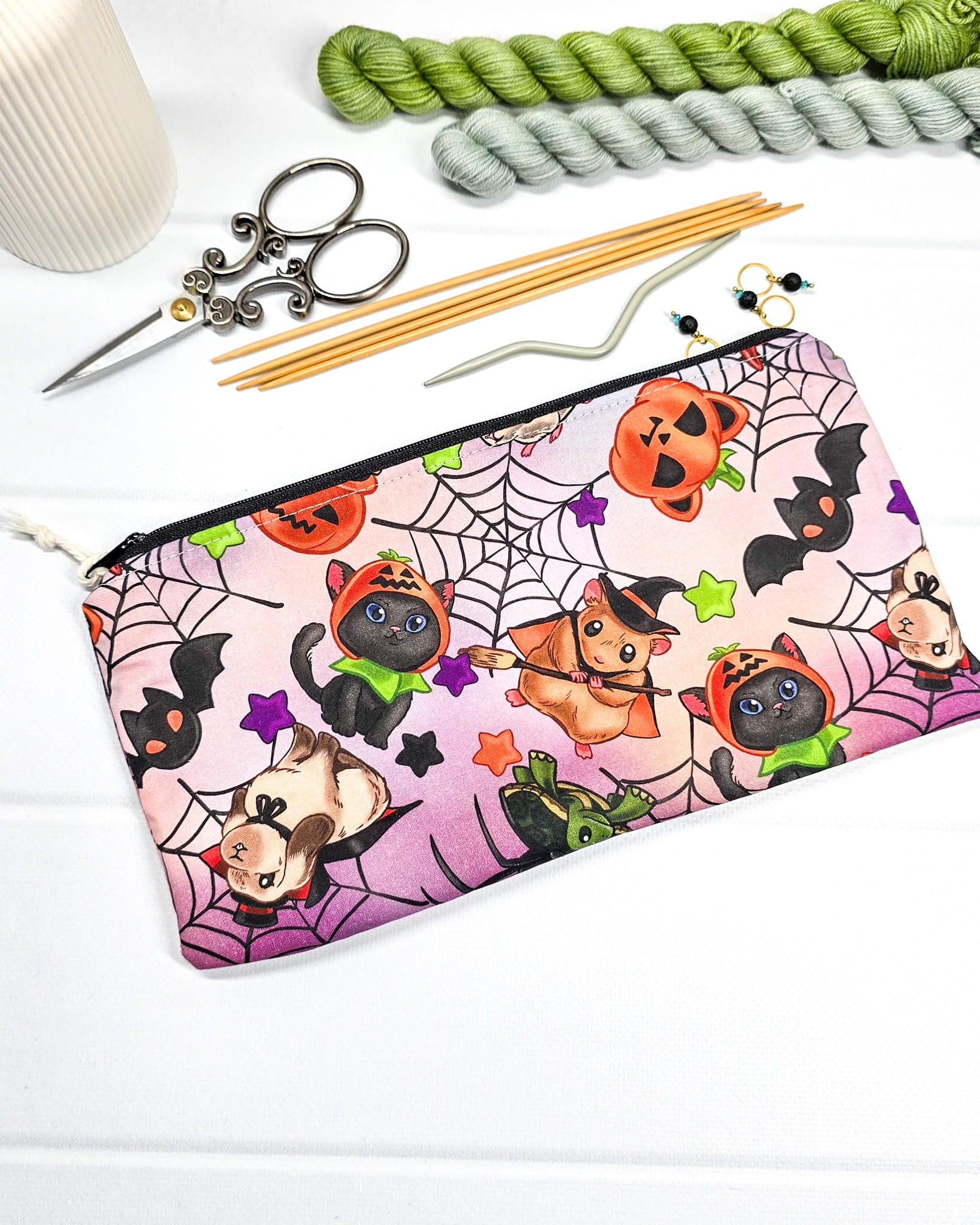 Kleine Reißverschlusstasche mit niedlichen verkleideten Halloween-Tieren, Spinnennetzen und Fledermäusen auf lila-rosa gemustertem Stoff mit weißem Kordel-Zipper. Handgenäht in Bayern von Nadelmikado.