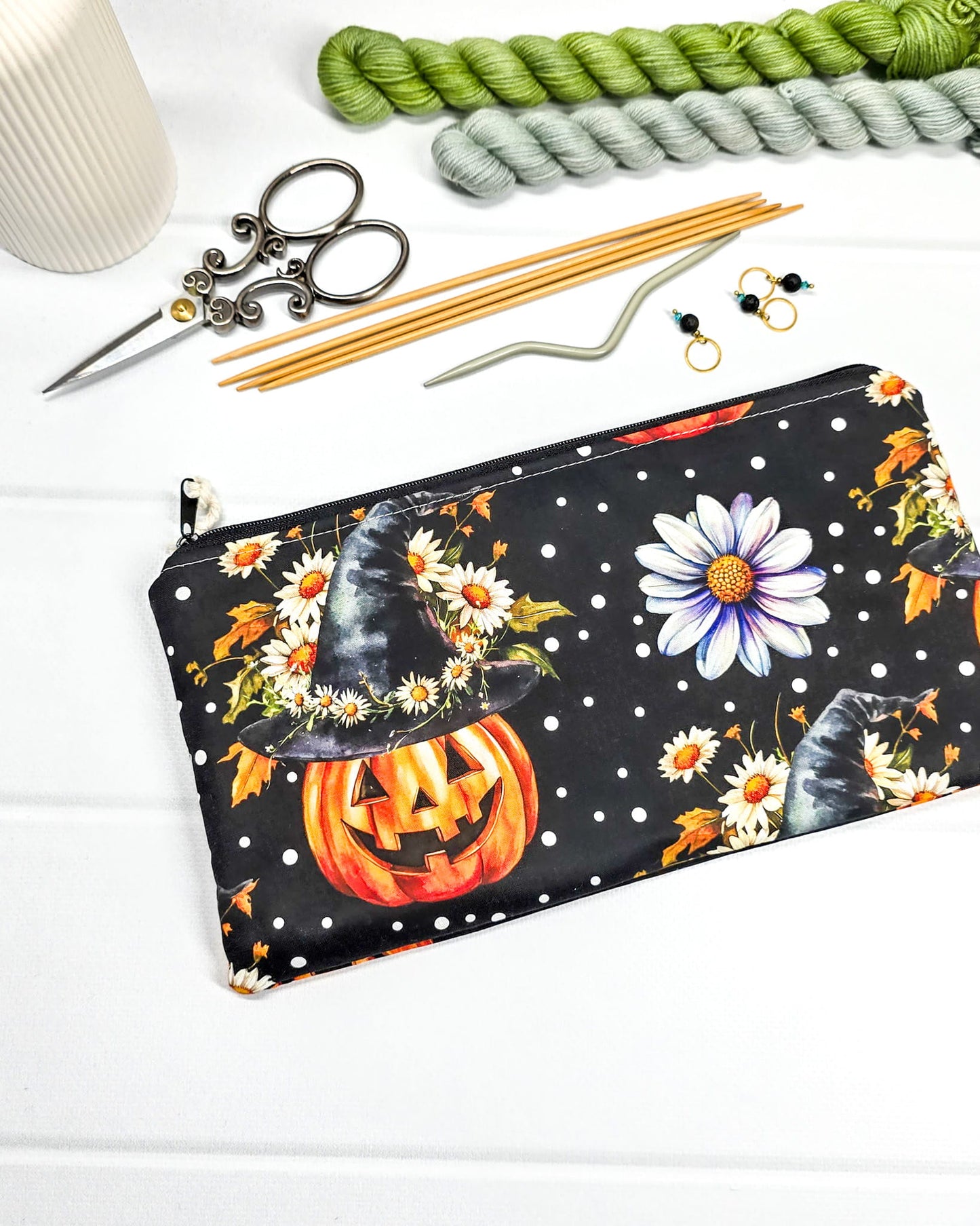 Längliche Zubehörtasche mit Reißverschluss und herbstlichen Kürbissen mit Hexenhüten, Blumen und Punkten auf schwarzem Grund. Handgenäht in Bayern von Nadelmikado.