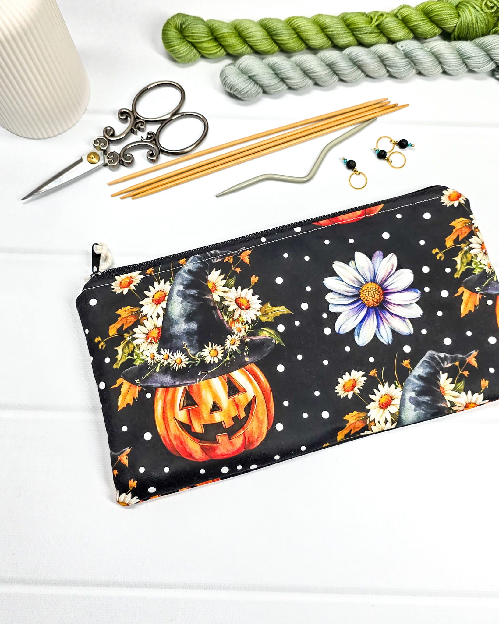 Längliche Zubehörtasche mit Reißverschluss und herbstlichen Kürbissen mit Hexenhüten, Blumen und Punkten auf schwarzem Grund. Handgenäht in Bayern von Nadelmikado.