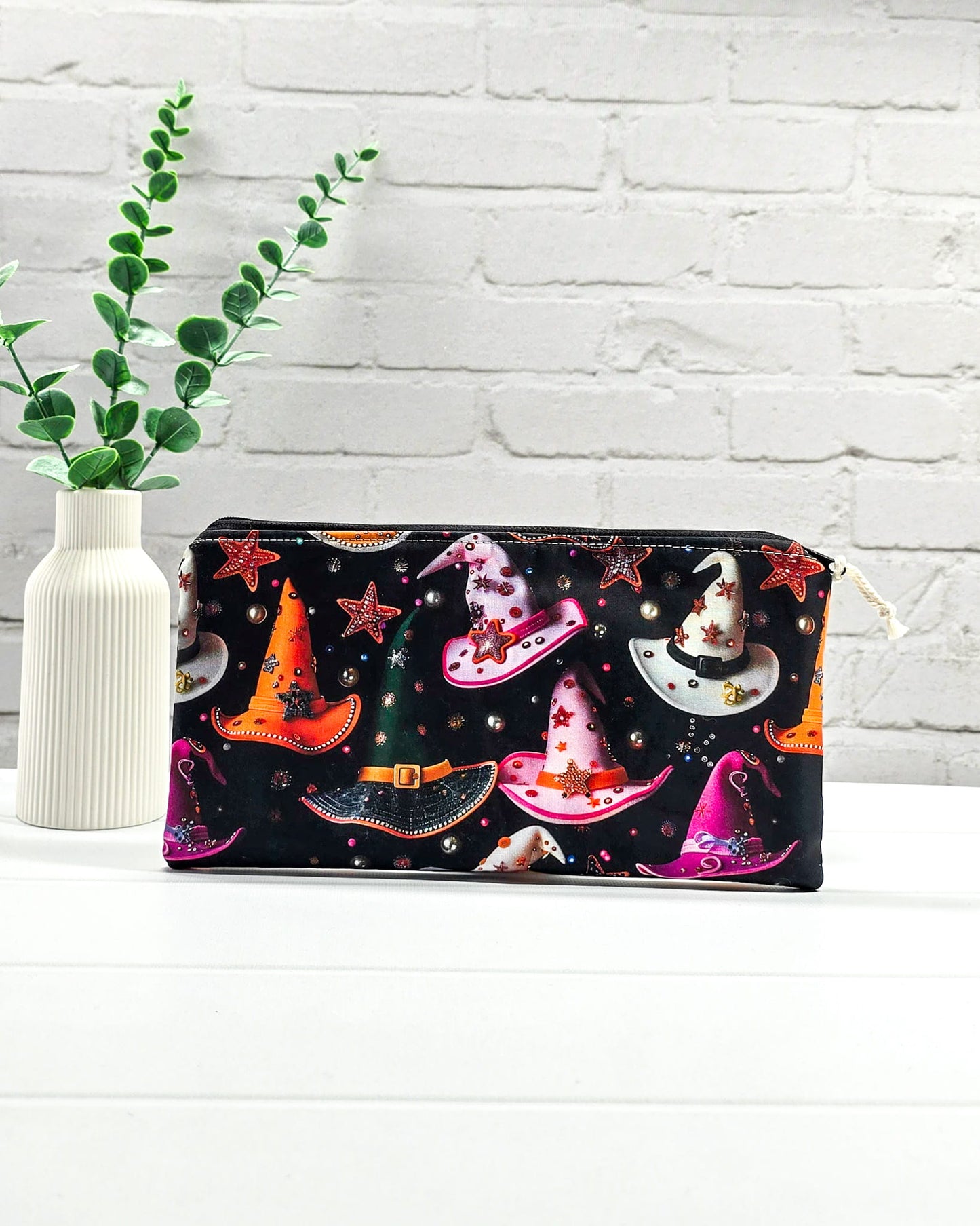 Kleine Reißverschlusstasche aus schwarzem Stoff mit bunten Hexenhüten als Zubehör-Etui für Handarbeiten. Genäht in Bayern von Nadelmikado.