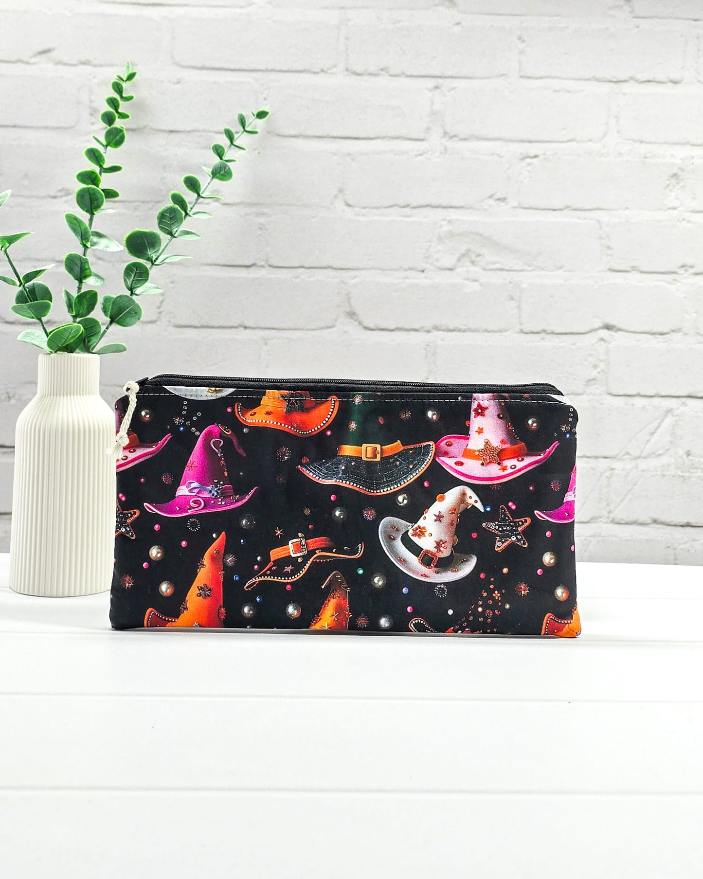Kleine Reißverschlusstasche aus schwarzem Stoff mit bunten Hexenhüten als Zubehör-Etui für Handarbeiten. Genäht in Bayern von Nadelmikado.