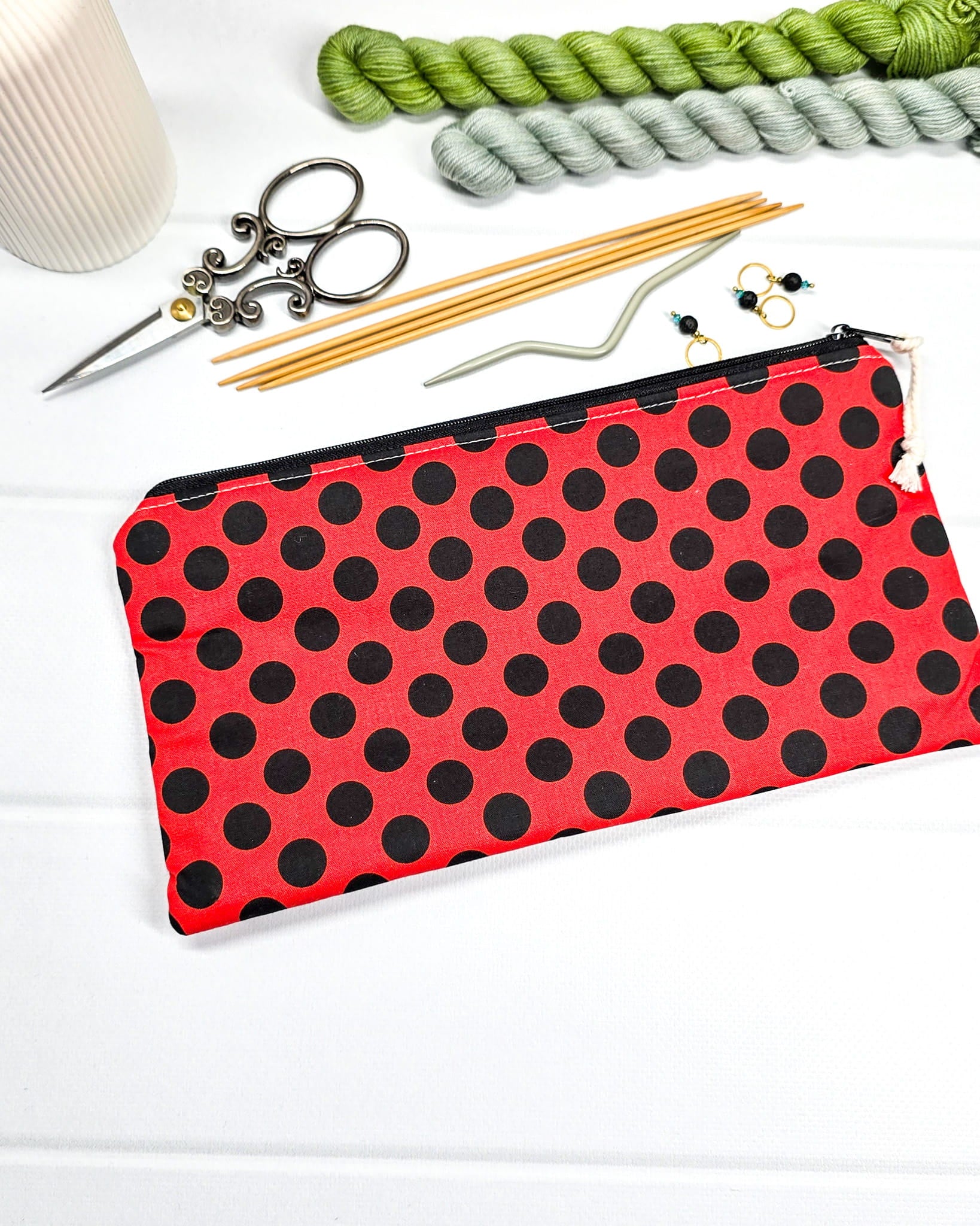 Flaches Etui mit schwarzem Reißverschluss und hellem Kordel-Zipper, Motiv mit großen schwarzen Punkten auf rotem Stoff. Handgenäht in Bayern von Nadelmikado.