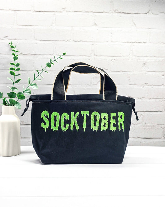 Bestickte Projekttasche Alva S aus schwarzem Canvas mit neongrünem Socktober-Schriftzug, handgenäht in Bayern von NadelMikado
