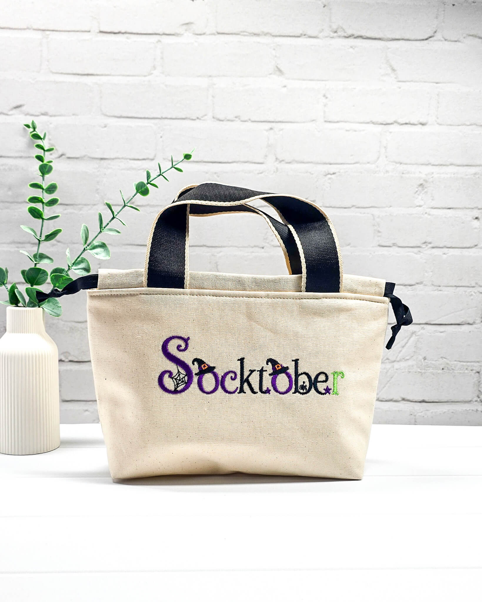 Stricktasche Alva S aus hellem Canvas mit besticktem Socktober-Schriftzug, Hexenhüten und Spinnennetz, handgenäht in Bayern von NadelMikado